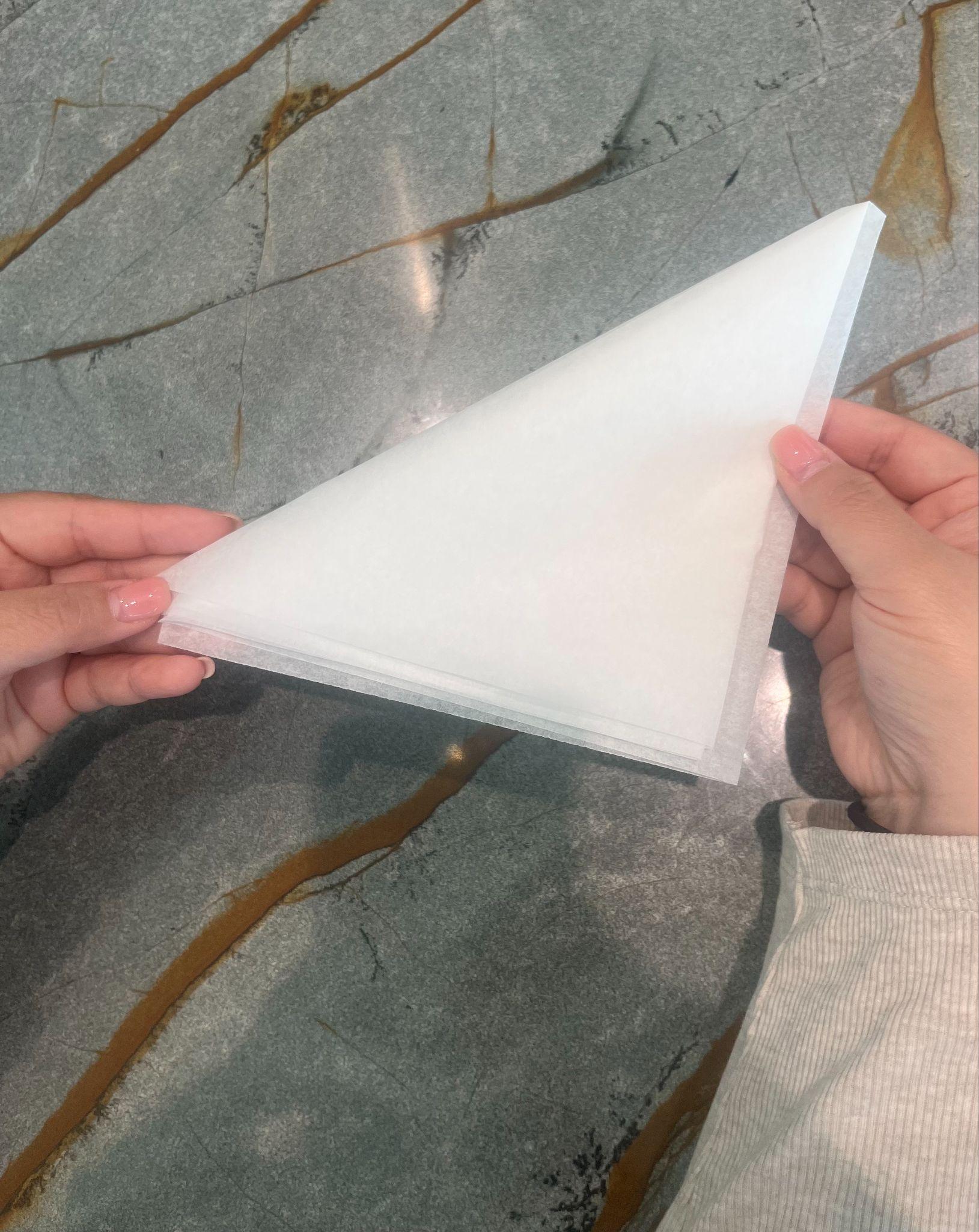 Hands folding the parchment into a right-angled triangle