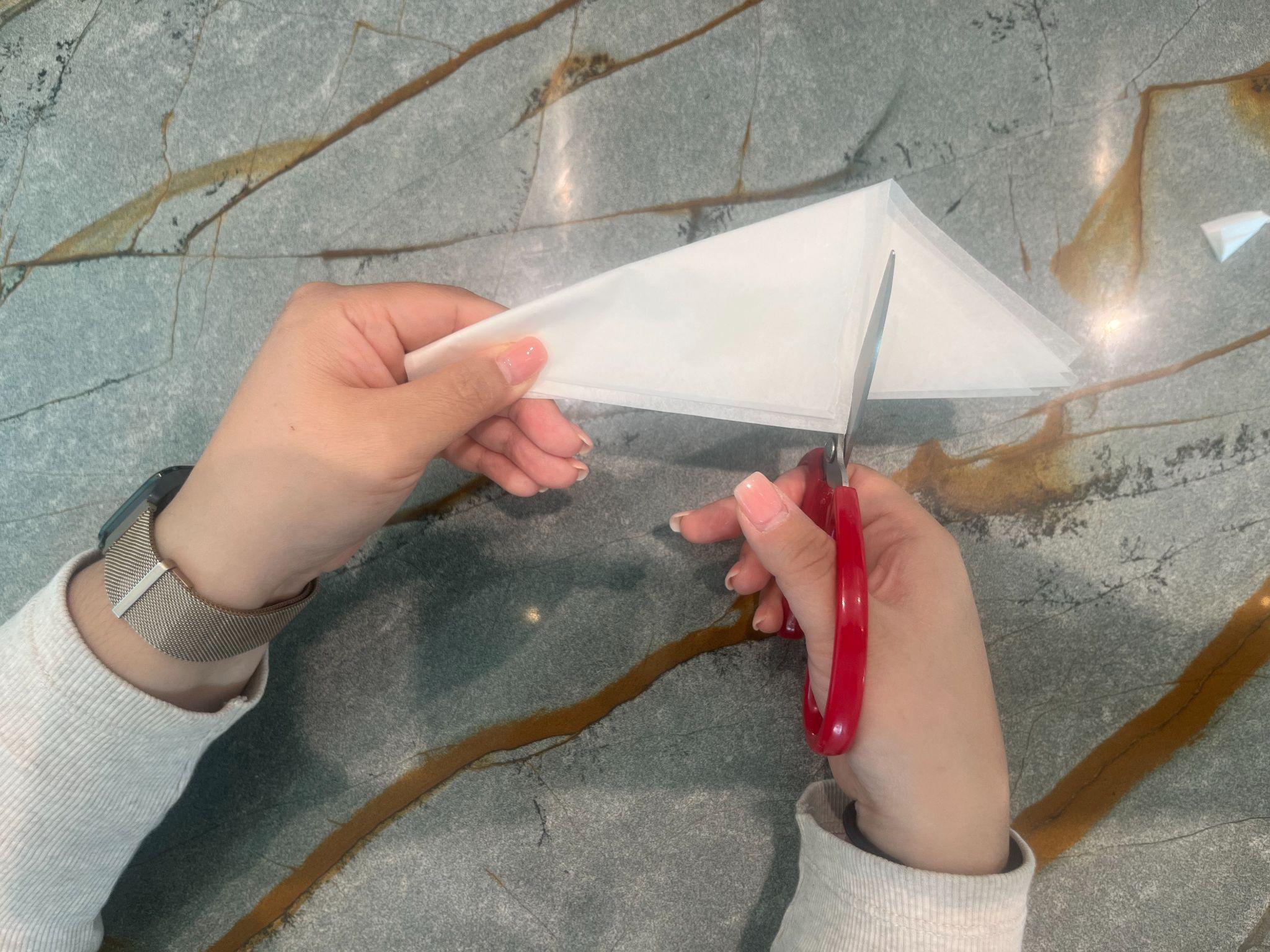 Hands trimming the outer edge of the folded parchment into a curve